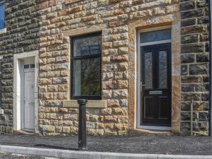 a brick building with a black door and two windows at Brun Cottage in Worsthorne