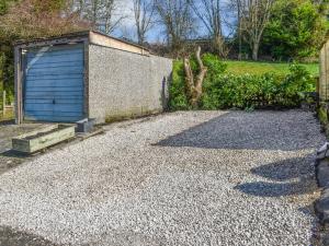 a gravel driveway with a blue garage in a yard at Brun Cottage in Worsthorne