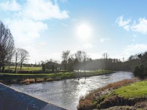 a river in a field with the sun in the sky at Brun Cottage in Worsthorne
