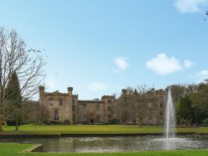 a castle with a pond and a fountain at Brun Cottage in Worsthorne +11 photos