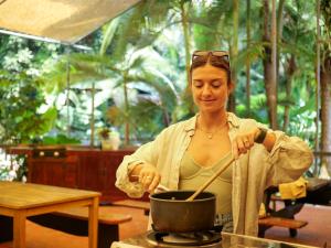 a woman stirring a pot on a stove at Safari Lodge in Cape Tribulation +66 photos