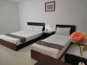 two beds in a hotel room with a flower at Townhouse Oak Vera Hotel Near Clark International Airport in Angeles
