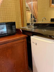 a kitchen with a microwave and a sink at Rocky Mountain Lodge & Suites in Renfrew