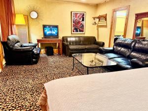 a living room with leather furniture and a flat screen tv at Rocky Mountain Lodge & Suites in Renfrew +48 photos