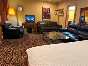 a living room with leather furniture and a flat screen tv at Rocky Mountain Lodge & Suites in Renfrew
