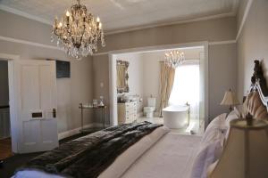 a bedroom with a large bed and a chandelier at The Kingsman boutique Hotel in Burgersdorp