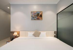 ein Schlafzimmer mit einem weißen Bett und einem Gemälde an der Wand in der Unterkunft Diamond Light Hotel in Hanoi