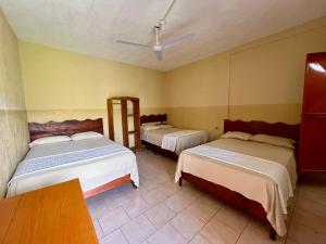 a room with two beds and a table in it at Hotel Israel in Guastatoya