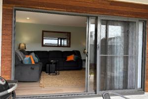 ein Wohnzimmer mit Sofa und Glasschiebetür in der Unterkunft Azure Abode in Broulee