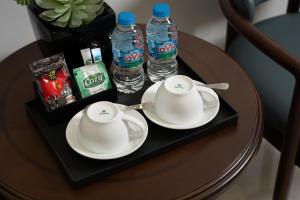 Ein Tablett mit zwei Tassen und zwei Flaschen Wasser auf einem Tisch in der Unterkunft Diamond Light Hotel in Hanoi + 47 Fotos