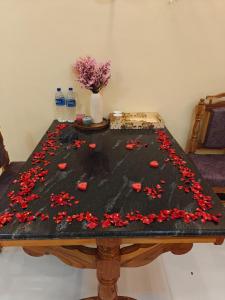 a table with red rose petals on it at Malathi Residency in Arumuganeri +34 photos