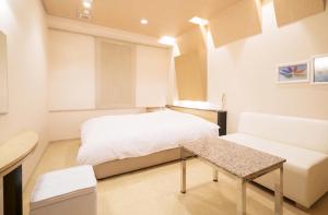 a bedroom with a bed and a table and a couch at Hotel Revoir in Izumi