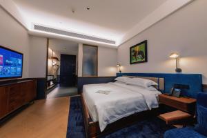 a bedroom with a bed and a flat screen tv at The Protons Guangzhou in Guangzhou