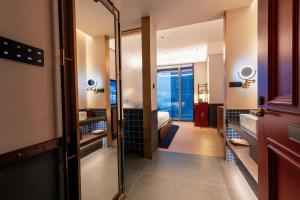 a hallway with a room with a bed and a mirror at The Protons Guangzhou in Guangzhou