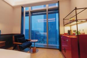 a bedroom with a large window with a chair and a desk at The Protons Guangzhou in Guangzhou