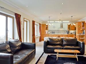 a living room with a leather couch and a kitchen at Waterside in Tighnabruaich