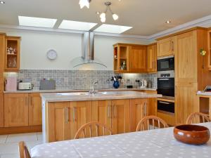 a kitchen with wooden cabinets and a sink and a table at Waterside in Tighnabruaich