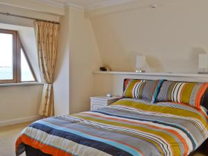 a bedroom with a bed with a colorful striped blanket at Waterside in Tighnabruaich +11 photos