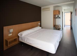 a bedroom with a large white bed with a wooden headboard at Hostal Mediterranea in Madrid