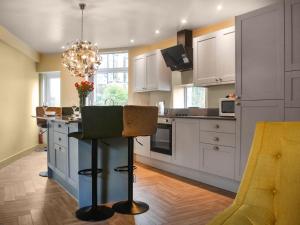 a kitchen with white cabinets and a table with a chair at Hollingreave House in Burnley