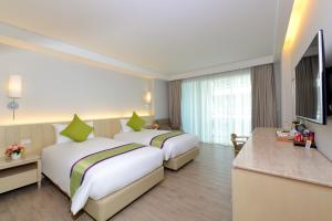 a hotel room with two beds and a television at Hisea Huahin Hotel in Hua Hin