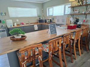 a kitchen with a large wooden counter with wooden chairs at Omidraai Opihoek in Boknes