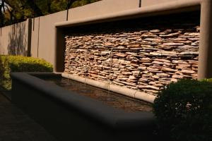 una pared de piedra con una fuente frente a un edificio en The Village in Hatfield en Pretoria