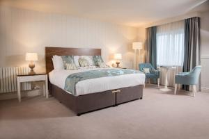 Waterfront Hotel Dungloe في دونغلو: غرفه فندقيه بسرير كبير وكرسيين