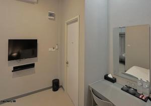 a bathroom with a television on a white wall at โรงแรมหลังสวนเพลส Langsuan place Hotel in Lang Suan +10 photos