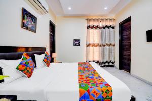 a bedroom with a large white bed with colorful pillows at FabHotel Sarala Residency in Noida