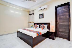 a bedroom with a large bed and a wooden door at FabHotel Sarala Residency in Noida
