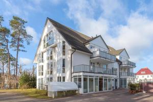 an exterior view of a white building with balconies at Fewo Lebensart - in bester Lage, mit TG und Balkon in Baabe