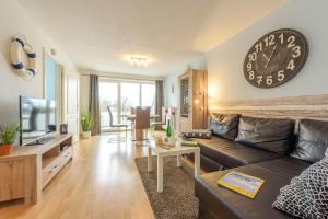 a living room with a couch and a clock on the wall at Fewo Lebensart - in bester Lage, mit TG und Balkon in Baabe