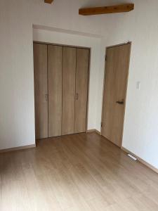 an empty room with two doors and wooden floors at shine house warabi2 in Warabi