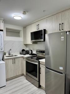 a kitchen with stainless steel appliances and wooden cabinets at Comfort 2 BR Vancouver! in Vancouver