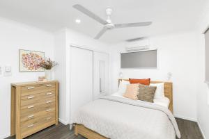 a white bedroom with a bed and a dresser at Hidden Gem - 3BR Home - Cairns in Edge Hill
