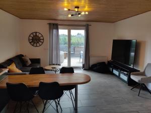 a living room with a table and a tv at Appartement Terrasse Jacuzzi du Pont Alsort 2-2 in Froid-Chapelle