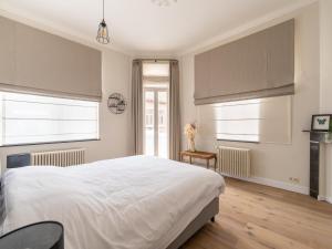 a bedroom with a large white bed and two windows at Scenic villa in Borgloon with garden in Borgloon