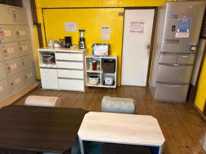 a room with a kitchen with a table and a refrigerator at Peace House Showa in Osaka