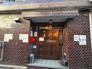 a brick building with a brown door in front at Peace House Showa in Osaka