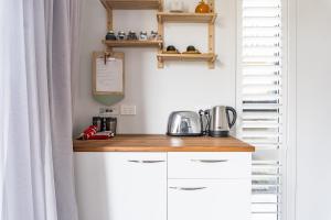 a kitchen with white cabinets and a wooden counter top at Walnut Studio in Raglan +6 photos
