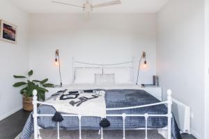 a white bed in a white bedroom with a plant at Walnut Studio in Raglan