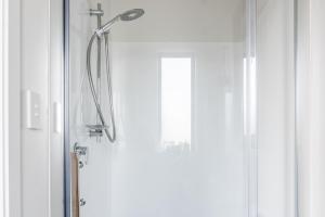 a shower with a glass door next to a window at Walnut Studio in Raglan
