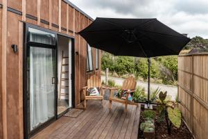 a patio with an umbrella and a chair on a deck at Walnut Studio in Raglan