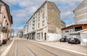 an empty street with cars parked in front of a building at Studio Cosy - Proche Tram et Gare de Grenoble in Fontaine
