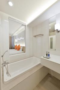 a bathroom with a tub and a sink and a mirror at Hisea Huahin Hotel in Hua Hin