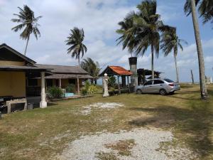 a car parked in front of a house with palm trees at Bayu Beach Chalet PCB in Kota Bharu +5 photos