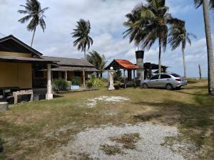 a car parked in front of a house with palm trees at Bayu Beach Chalet PCB in Kota Bharu