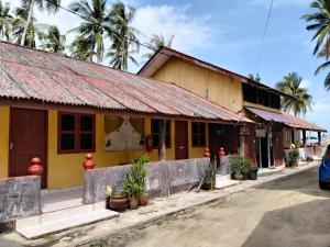 a yellow building with a red roof next to a street at Bayu Beach Chalet PCB in Kota Bharu