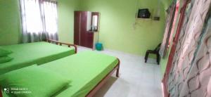 a green room with two beds and a window at Bayu Beach Chalet PCB in Kota Bharu